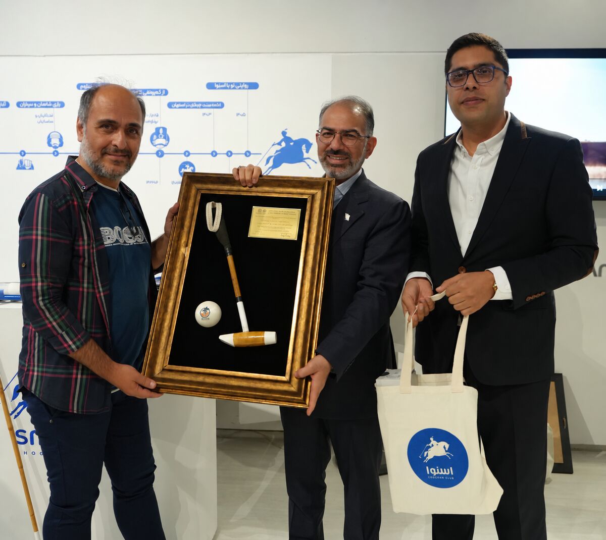 A group of men holding a picture frame  Description automatically generated